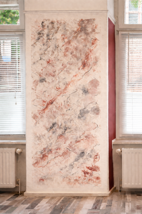 Wand mit abstraktem Farbdesign in sanften Rot- und Grautönen.